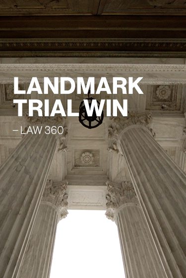 Landmark trial win text overlaid on white pillars